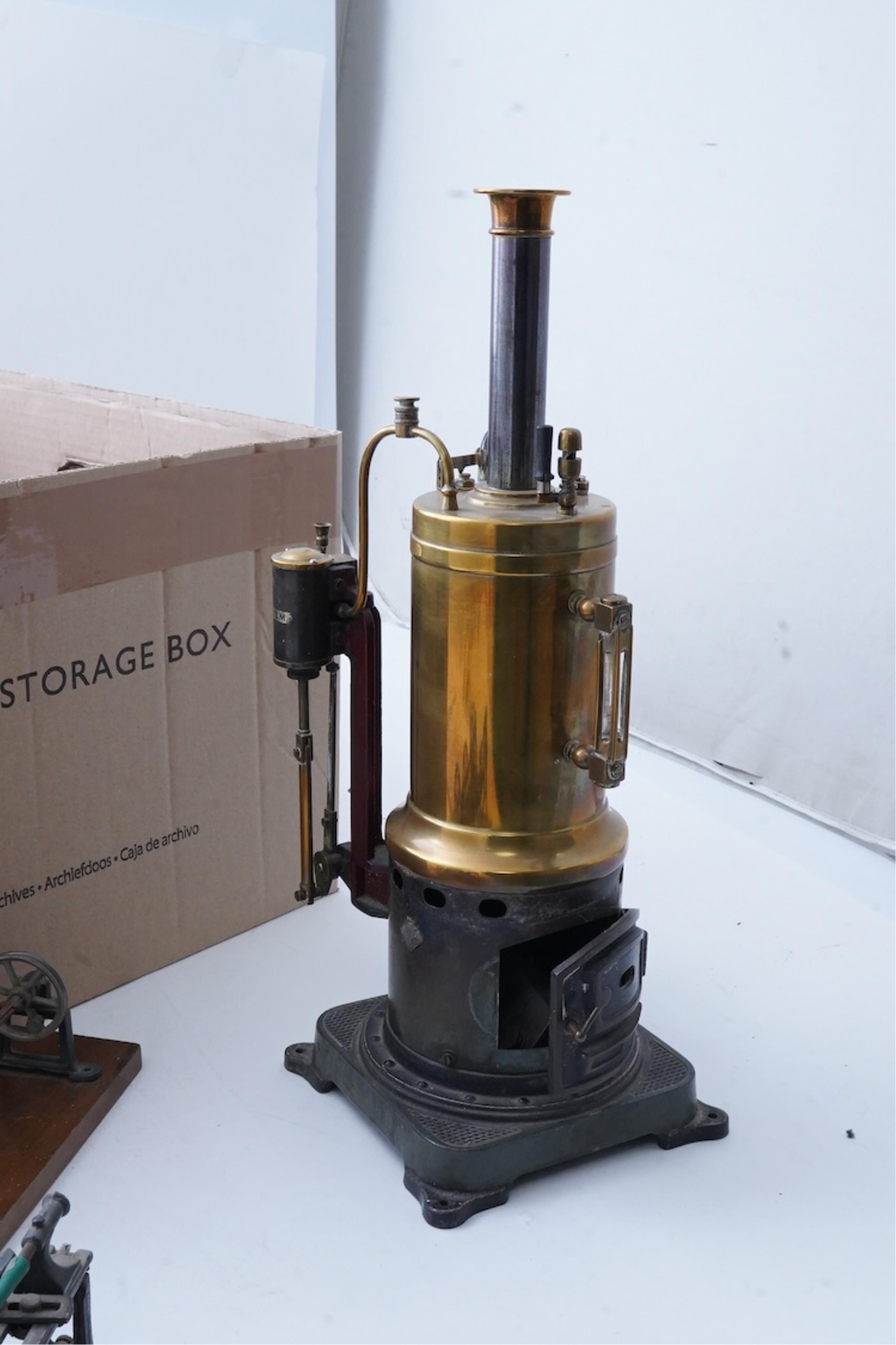 An early 20th century Bing live steam single cylinder vertical stationary engine, of brass, tinplate and cast iron construction, 38cm high, 10.5cm diameter flywheel, complete with the burner, together with a steam plant